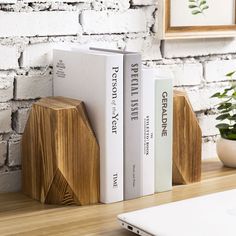 two books are placed next to each other on a wooden shelf near a laptop computer