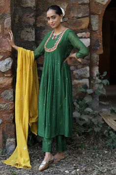 Green fine chanderi anarkali with sequins, thread and mirror embroidered empire yoke and sleeve hems. Comes with cupro silk pant with small coin detailing on hem and a mustard yellow kasab work dupatta.
Components: 3
Pattern: Embroidered
Type Of Work: Sequins, Thread, Mirror
Neckline: Round
Sleeve Type: Three quarter
Fabric: Fine chanderi, Pant : Cupro silk
Color: Green
Other Details: 
Length :
Kurta : 48 inches
Pant : 38 inches
Closure : Anarkali - Front potli button
Occasion: Mehendi and Haldi Potli Button, Chanderi Anarkali, Heavy Dresses, Silk Pant, Boutique Collection, Green Sequins, Silk Pants, Clothes Horse, Pant Set