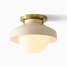 an overhead light fixture with a white glass shade on the top and gold trimmings