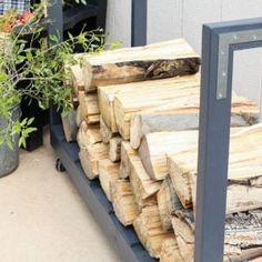 a pile of wood sitting on top of a metal shelf next to a potted plant