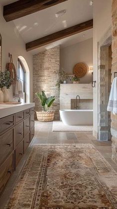 a large bathroom with stone walls and flooring is shown in this image, there are two sinks on the far side of the bathtub