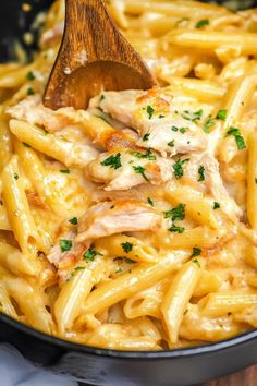 pasta with chicken and parmesan cheese in a skillet on a wooden spoon