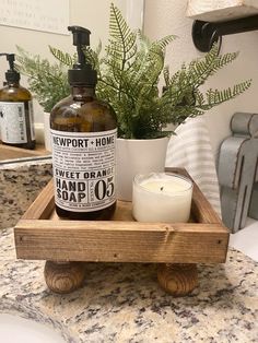 a bottle of soap sitting on top of a wooden tray next to a white candle