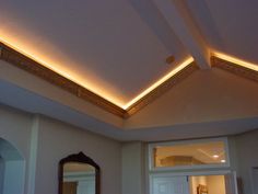 a room with a mirror, door and lights on the ceiling is lit by recessed lighting