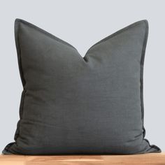 a dark gray pillow sitting on top of a wooden table