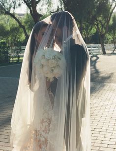 a bride and groom kissing under a veil