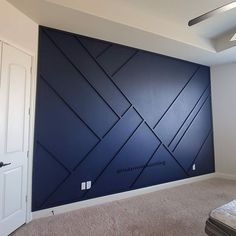 an empty room with a bed and blue wall in the corner, next to a white door