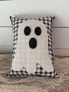 a black and white pillow with a ghost face on it