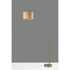 a floor lamp with a beige shade on the top and a gold metal base, against a gray background