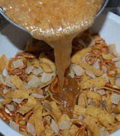 a bowl filled with cheetos and pretzels being poured into the bowl