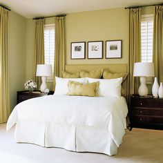 a bedroom with green walls, white bedding and two lamps on either side of the bed