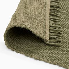 a green rug with fringes laying on top of it