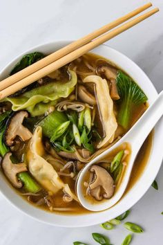 a white bowl filled with soup and chopsticks on top of it, next to some green beans