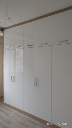 an empty room with white cabinets and wood flooring on the walls, in front of a window