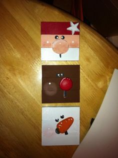 three cards with different pictures on them sitting on top of a wooden table in the shape of santa claus