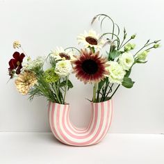 a vase filled with flowers sitting on top of a white table next to a wall