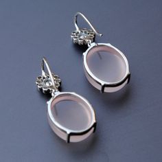 "Subtle oval shaped cabochon rose quartz, dangling from an oval diamond flower, set in 14k white gold, these stunners make for those perfect and unique wedding earrings. An exclusive piece from our shop, these earrings are absolutely to die for..! Oval Diamond - Dangle Earrings - 14K Gold - Rose Quartz - Wedding Earrings - Gemstone Bridal Earrings * Gemstone 1 : Natural Diamonds. * Diamond Wt. : 0.37 Cts (Oval Cut) + 0.25 cts (Round) * Color-Clarity Grade : G Color, Vs Purity * Gemstone 2 : Natu Unique Wedding Earrings, Rose Quartz Wedding, Pin It Button, Big Dangle Earrings, Oval Diamond Engagement, Diamond Tiara, Rose Gold Quartz, Diamond Crown, Earrings Gemstone