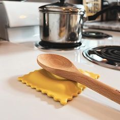 a wooden spoon sitting on top of a yellow spatula next to a stovetop