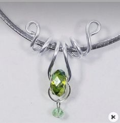 a silver necklace with a green stone hanging from it