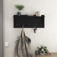 a bag hanging on a wall next to a potted plant and two bookshelves