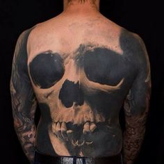 a man with tattoos on his back has a skull and skulls tattoo on his chest