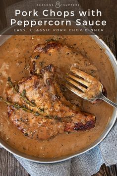 a pan filled with meat and gravy on top of a wooden table