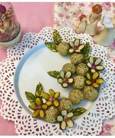 there is a white plate with flowers and nuts on it, next to a glass jar