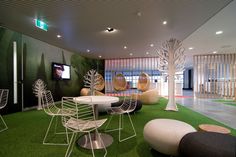 a room with chairs, tables and television on the wall next to a green carpeted floor