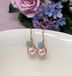 These one of a kind flowering beauties feature soft, blush pink Swarovski Crystal pearls that are meticulously wrapped in 14kt yellow gold filled wire. The braided detailing looks amazing with these pearls. Accented with gold-dusted, aqua Czech glass flowers and gracefully suspended from handcrafted French ear wires. These are perfect for Spring, Summer and for bridesmaids gifts! - All components are 14kt yellow gold filled. - Swarovski Crystal pearls, Czech Glass flower beads. - Pearl dangles a Whimsical Pink Dangle Flower Earrings, Feminine Jewelry With Matching Earrings For Spring, Handmade Pink Teardrop Flower Earrings, Delicate Dangle Earrings For Spring, Whimsical Pink Earrings With Flower Charm, Elegant Teardrop Earrings For Spring, Rose Gold Drop Flower Earrings For Spring, Pink Earrings With Handmade Flowers For Spring, Delicate Drop Earrings For Spring