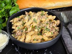 a black bowl filled with pasta and meat