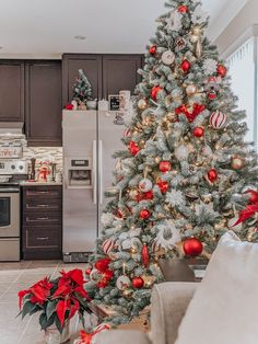 a decorated christmas tree in the middle of a living room with red and silver ornaments