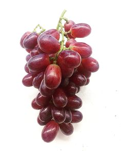 a bunch of red grapes on a white surface