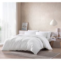 a bed with white comforter and pillows in a room