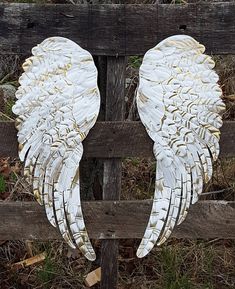 two white angel wings sitting on top of a wooden fence