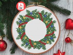 a cross stitch christmas ornament hanging on a tree branch with ornaments around it