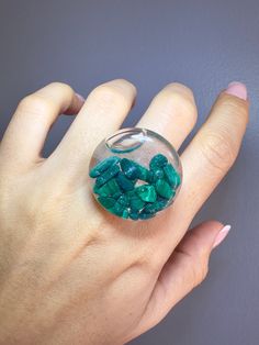 Immerse yourself in the magic of nature with this stunning 27mm glass bubble ring. Inside, you'll find high-quality natural Malachite stones, carefully encapsulated in liquid with subtle glittery flakes that dance with every movement. The ring band, made of transparent resin, adds an elegant and unique touch to this already beautiful piece. This unique 27mm ring shaker is not only a dazzling piece of jewelry but also a conversation starter that is sure to capture attention. Malachite is revered for its ability to protect against negative energies and pollutants, as well as promote emotional balance and spiritual growth. Choose elegance and uniqueness with this beautiful ring that embodies nature's beauty at its finest. Note: It is recommended to avoid damage on the ring since the surface i Ring Resin, Malachite Crystal, Bubble Ring, Glass Bubble, Transparent Resin, Glass Ring, Malachite Stone, Resin Ring, Glass Rings