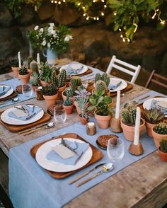 the table is set with succulents and place settings for an outdoor dinner