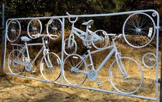 there are many bicycles on this metal bike rack in the grass and some bushes behind it