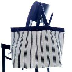 a black and white striped tote bag hanging from a chair with the seat up