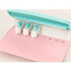 three blue and white staplers sitting on top of a pink piece of paper