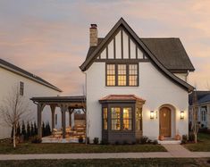 a white house with black trim on the front and side windows at dusk in suburban neighborhood