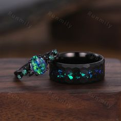 two rings with green and blue fire opal in them on top of a wooden table