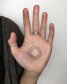 a person's hand with a small tattoo on the middle of their left palm