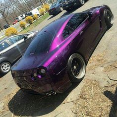 a purple sports car parked in a parking lot next to other cars on the street