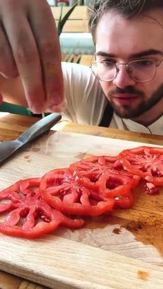 a man cutting tomatoes on a wooden cutting board