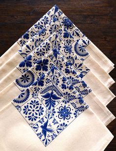 four blue and white napkins sitting on top of a wooden table