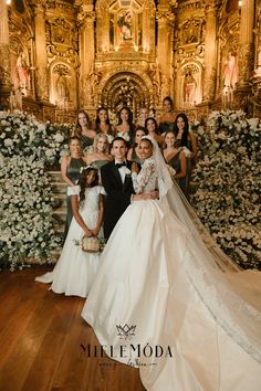 the bride and groom are posing with their bridal party in front of an elaborately decorated wall