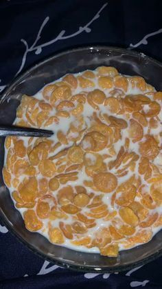 a bowl filled with oranges and cream on top of a blue table cloth next to a spoon