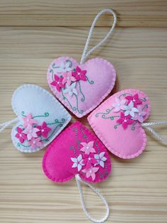 four pink and white felt hearts with flowers on them