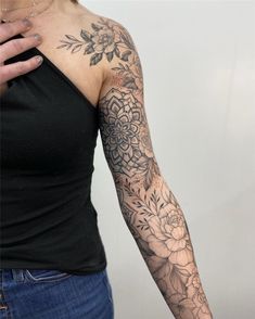 a woman's arm with flowers and leaves tattooed on her left arm, in front of a white background